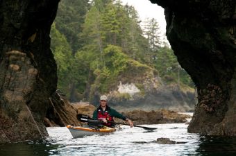 West Coast Expeditions owner Dave Pinel paddling under a sea arch