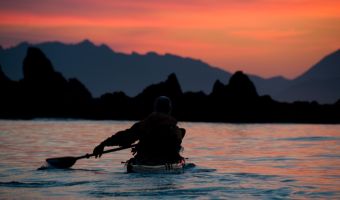 David Pinel paddling toward sunset over the Brooks Peninsula
