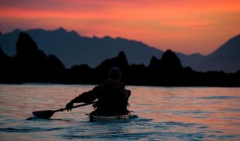 image by Bruce Kirkby David Pinel paddling toward sunset over the Brooks Peninsula